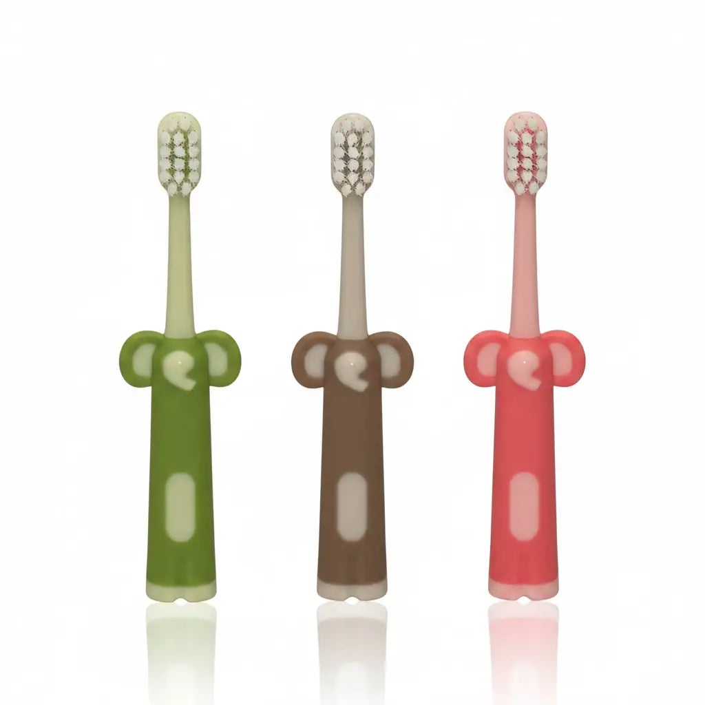 Assorted Kids Ultra Soft Toothbrushes with elephant-shaped easy-grip handles in green, beige and pink, arranged on a white background with subtle reflections.