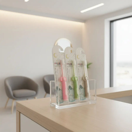 Individually wrapped Kids Ultra Soft Toothbrushes in assorted colours displayed on a dental clinic reception counter, showing convenient packaging for patient packs and everyday distribution.