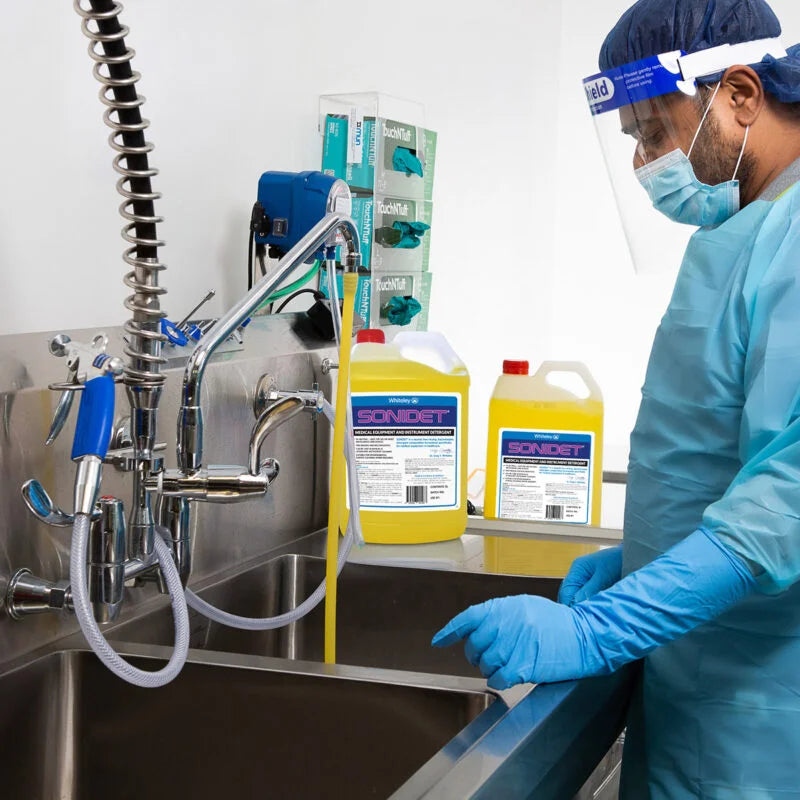 Person using Sonidet 5L pH neutral instrument detergent in a clinical setting for cleaning medical and dental instruments prior to sterilisation in ultrasonic and manual cleaning systems